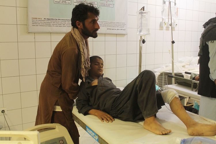 Seorang warga di Kunduz, Afghanistan, menemani anak yang menjadi korban serangan udara pasukan pemerintah Senin (2/4/2018). Pemerintah menyebut, serangan tersebut menyasar komandan Taliban yang tengah berkumpul untuk merencanakan serangan.