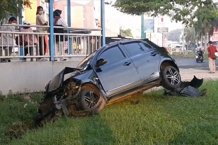 Sebuah mobil mini sedan mengalami kecelakaan tunggal di depan halte busway Puri Beta 1, Kota Tangerang, Minggu (25/9/2022). Pasangan suami istri yang ingin berangkat kondangan mengendari mobil itu harus di bawa ke rumah sakit.