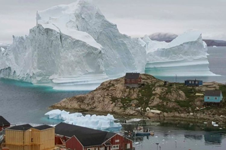 Gunung es diperkirakan seberat 11 juta ton terlihat di dekat sebuah pulau dengan beberapa bengunan di Greenland.