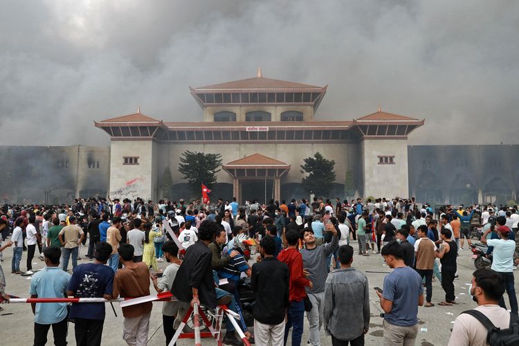 Para peserta demo Nepal berkumpul di depan gedung parlemen yang kebakaran di Kathmandu, 9 September 2025. Pemerintah sementara di bawah Sushila Karki bentuk tim khusus usai demo antikorupsi memicu korban tewas 74 orang dan lebih dari 2.100 orang luka.