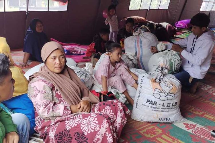 Istri Sirun, Juni (45) dan keluarganya saat berada di tempat pengungsian di pinggir jalan di Nagari Maringgiang, Kecamatan Tigo Nagari, Kabupaten Pasaman, Provinsi Sumatera Barat, Sabtu (26/2/2022).