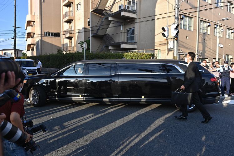 Mobil yang diyakini membawa jenazah mantan perdana menteri Jepang Shinzo Abe melewati sekumpulan polisi dan awak media di luar Rumah Sakit Universitas Nara di Kashihara, prefektur Nara, Sabtu (9/7/2022) pagi. Shinzo Abe Mantan PM Jepang tewas ditembak di kota Nara pada Jumat (8/7/2022).