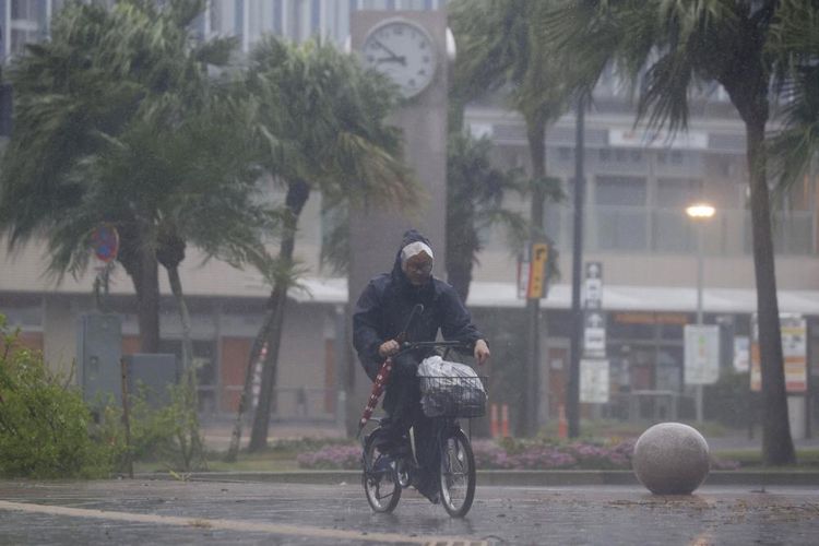 Seorang pria bersepeda melewati hujan di Miyazaki, Jepang selatan, Minggu (18/9/2022), saat topan kuat yang mendekati Jepang selatan pada Minggu menerjang wilayah itu dengan angin kencang dan hujan lebat. 