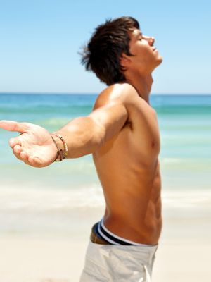 Photo of a  young male relaxing on the beach with his hands stretched