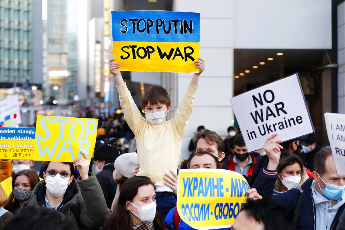 Orang-orang termasuk orang Rusia yang tinggal di Jepang mengangkat plakat untuk memprotes invasi Rusia ke Ukraina, di distrik Shinjuku Tokyo, Jepang, Sabtu, 26 Februari 2022. 