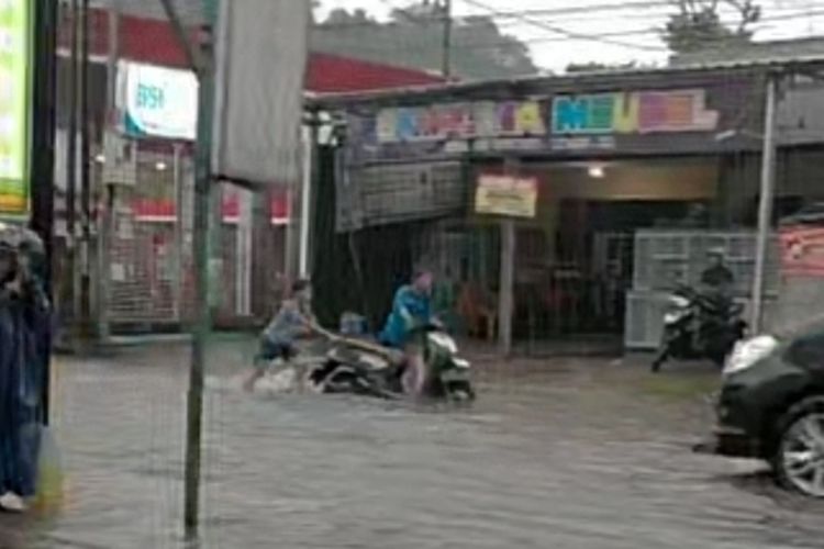 Pengendara motor yang mogok terpaksa didorong warga yang hujan-hujanan di lokasi banjir tiap hujan deras di Jalan AH Nasution, Mangkubumi, Kota Tasikmalaya, Jawa Barat, Senin (16/12/2024).