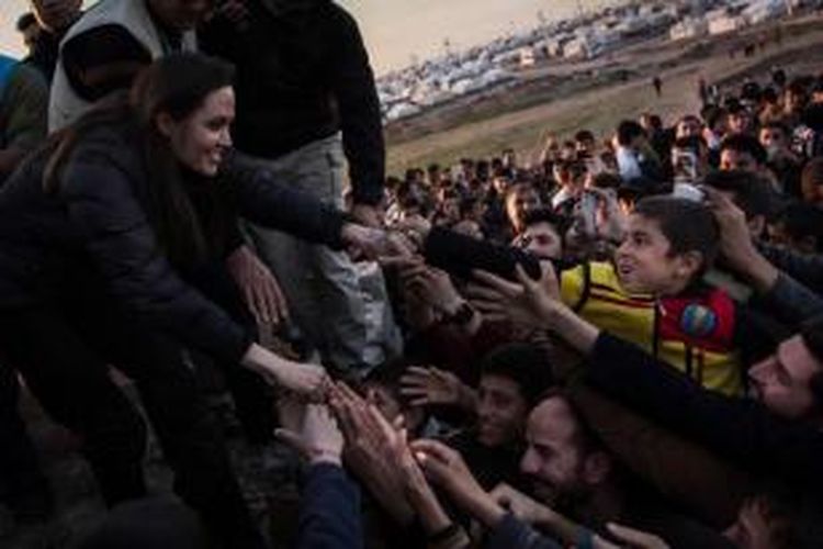Aktris asal AS yang menjadi duta UNHCR, Angelina Jolie membalas salam dari para pengungsi di kamp Khanke, beberapa kilometres dari perbatasan Turki dan Irak di Provinsi Dohuk, Minggu (25/1/2015).