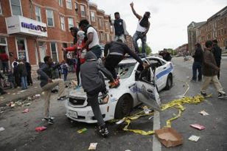 Para pengunjuk rasa menghancurkan sebuah mobil polisi dalam kerusuhan bernuansa rasial di kota Baltimore, Maryland, AS, yang dipicu kematian seorang pemuda kulit hitam dalam tahanan polisi.