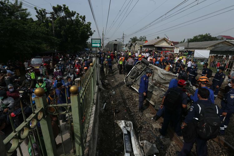 Petugas melakukan evakuasi mobil Mobilio dengan nomor polisi B 1563 NYZ yang tertabrak KRL Commuter Line di Depok, Jawa Barat, Rabu (20/4/2022). Akibat kejadian ini jadwal KRL dari Depok menuju Jakarta terganggu.