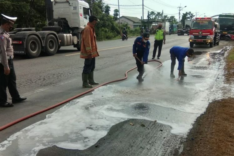 Petugas membersihkan cairan kimia yang tercecer di Jalan Raya Desa Rejosari, Kecamatan Deket, Lamongan, usai seorang pengendara sepeda motor tergelincir dan tewas di lokasi, Senin (17/1/2022).