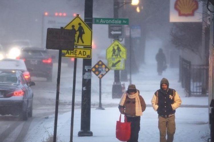 Pejalan kaki melewati trotoar yang tertutup salju saat suhu membeku di satu digit pada 22 Desember 2022 di Chicago, Illinois. Sistem cuaca musim dingin yang membawa salju, angin kencang, dan suhu di bawah nol telah mendatangkan malapetaka di sebagian besar daerah menjelang liburan. Angin kencang diperkirakan akan bergabung dengan suhu di bawah nol besok yang mendorong angin dingin di Chicago menjadi sekitar -40 derajat. 
