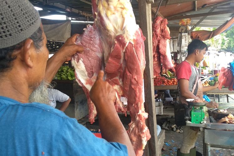 Pak Haji memotong daging sapi. Dua hari menjelang lebaran, harga daging sapi naik Rp 20.000 menjadi Rp 140.000 per kilogram.