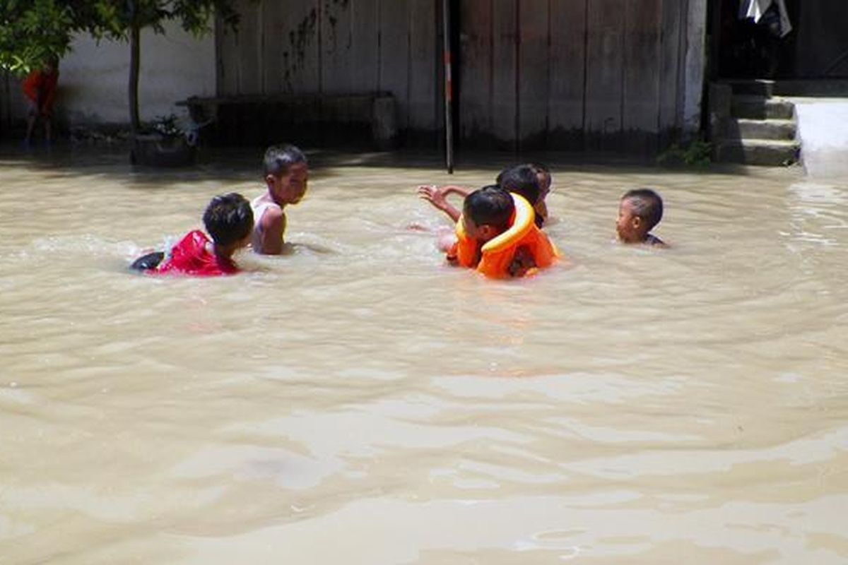 Anak-anak di Desa Dukun Anyar di Kecamatan Dukun, Gresik, sedang asyik bermain air banjir yang merendam desanya, Minggu (27/11/2016).