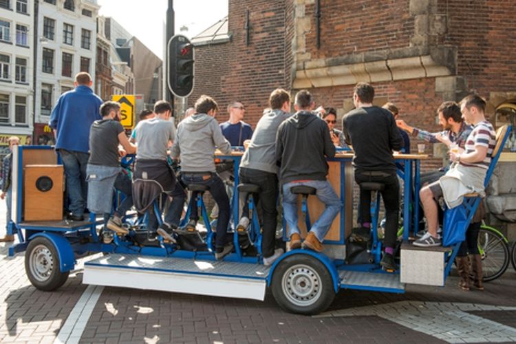 Sejumlah orang menikmati bir di beer bike di Amsterdam. Mulai hari ini, konsep minum bir sambil mengayuh sepeda itu dilarang beroperasi karena dinilai mengganggu ketertiban umum (1/11/2017).