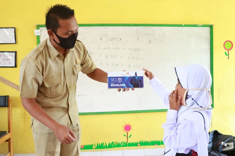 Ziesvario, guru SDN 32 Kampung Baru Tanjung Jabung Barat Jambi menggunakan masker mengajar matematika.