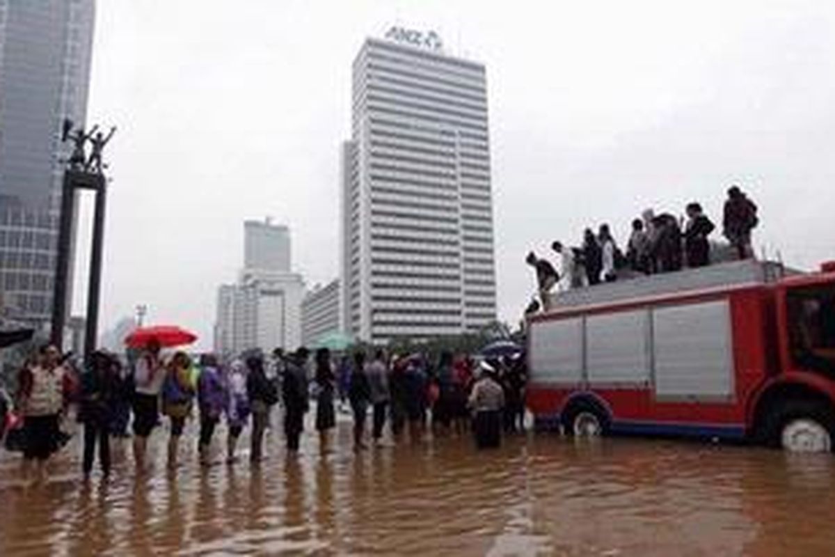 Petugas Dinas Pemadam Kebakaran DKI mengangkut karyawan yang terjebak banjir di Bundaran Hotel Indonesia, Jakarta, menggunakan mobil pemadam kebakaran, Kamis (17/1/2013). Curah hujan tinggi mengakibatkan dinding sungai Banjir Kanal Barat jebol sehingga air membanjiri ruas Jalan Latuharhari, Dukuh Atas hingga Bundaran Hotel Indonesia. KOMPAS/LUCKY PRANSISKA