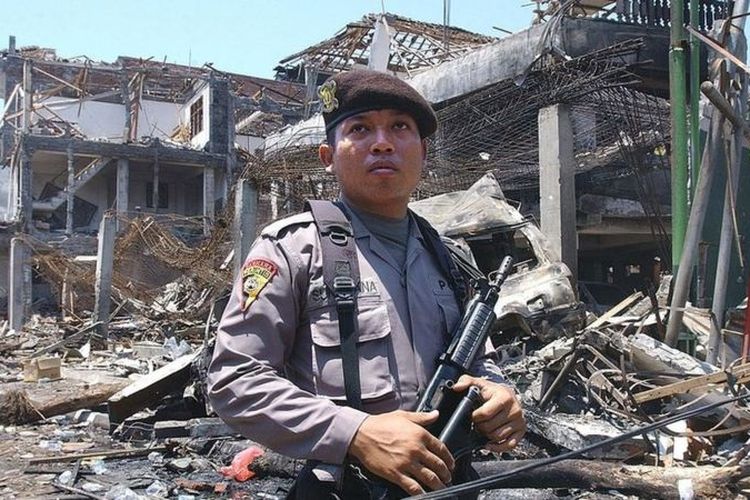 Seorang aparat polisi berjaga di depan salah-satu lokasi ledakan bom di Kuta, Bali, 12 Oktober 2002, yang menewaskan 202 orang.