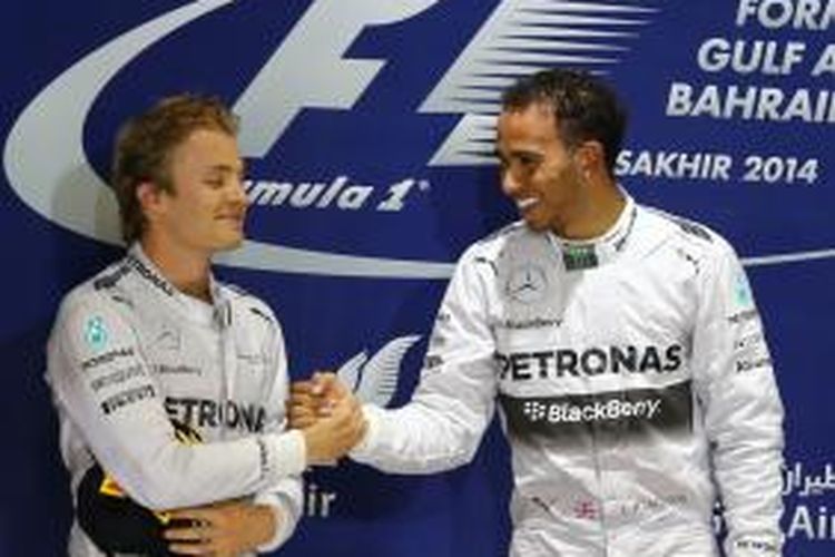 Pebalap Mercedes Lewis Hamilton (kanan) dan Nico Rosberg bersalaman di atas podium Sirkuit Internasional Bahrain setelah menyelesaikan GP Bahrain, Minggu (6/4/2014). Hamilton finis pertama sementara Rosberg kedua. MARWAN NAAMANI 