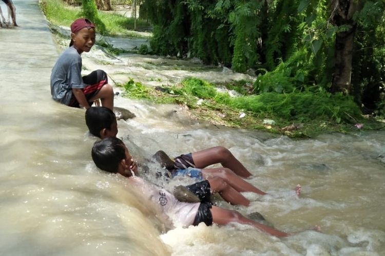 Sejumlah anak bermain di jalan Desa Babakan, Kecamatan Losari, Kabupaten Brebes, Jawa Tengah yang terendam air akibat hujan deras yang mengakibatkan tanggul jebol, Senin (17/2/2020)