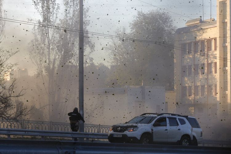 Seorang petugas polisi menyaksikan puing-puing batu dan tanah beterbangan di udara saat drone kamikaze Rusia menghantam pusat ibu kota Kyiv, Ukraina, Senin, 17 Oktober 2022. 