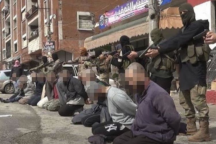 Dalam gambar nampak 10 anggota ISIS dijejer di jalan dengan anggota kelompok ekstremis rival Tahrir al-Sham bersiap menembak mereka.