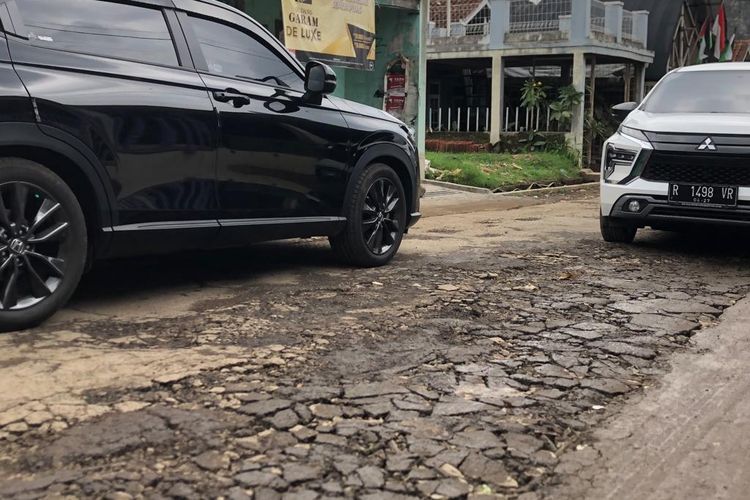 Lapisan aspal di Jalan Sersan Bajuri, Desa Cihideung, Kecamatan Parongpong, Kabupaten Bandung Barat (KBB), Jawa Barat mengelupas berantakan setelah diterjang hujan deras semalaman, Minggu (24/12/2023).