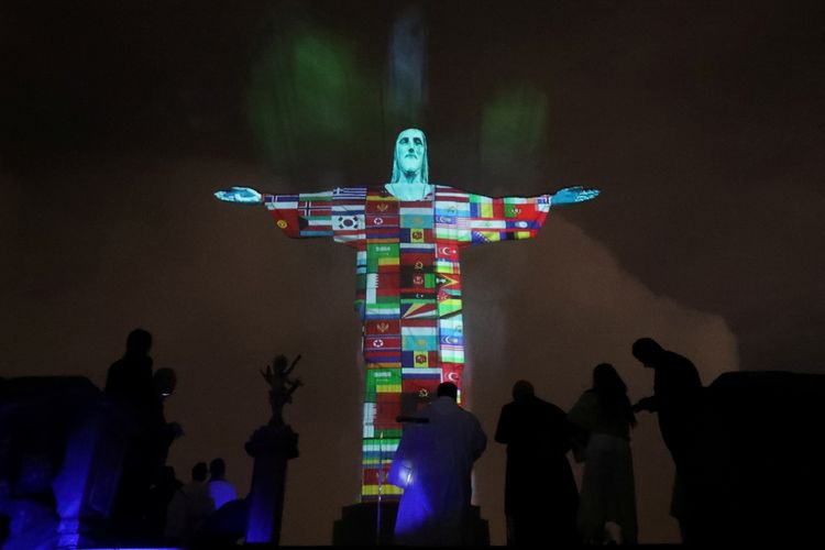 Patung Kristus Penebus dihiasi dengan bendera negara yang terpapar virus corona di Rio de Janeiro, Brasil, pada 18 Maret 2020.