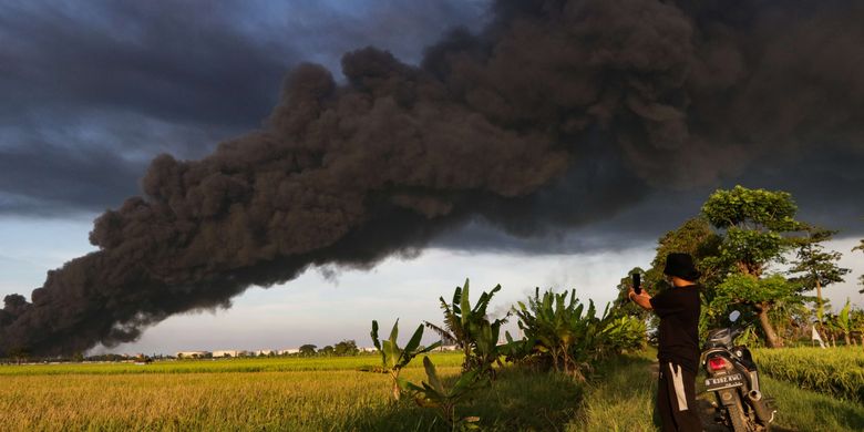 Warga menyaksikan kebakaran kilang minyak milik Pertamina RU VI di Balongan, Indramayu, Jawa Barat, dari kejauhan, Senin (29/3/2021).  Tangki di kilang minyak milik Pertamina ini terbakar pada Senin, pukul 00.45 WIB.