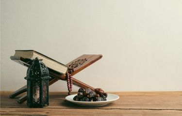 Ilustrasi Al Quran dan kurma dalam momen Ramadhan. Jumlah bacaan Al Quran agar khatam saat akhir Ramadhan. (Dok. Shutterstock/ Rembolle)