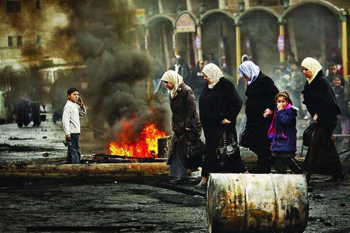 Perempuan Palestina menyeberang sebuah jalan pada saat terjadi serangan tentara Israel, saat terjadi aksi unjuk rasa menentang serangan tentara Israel ke Gaza di kamp pengungsi Shuafat di pinggiran Jerusalem, Senin (29/12).  