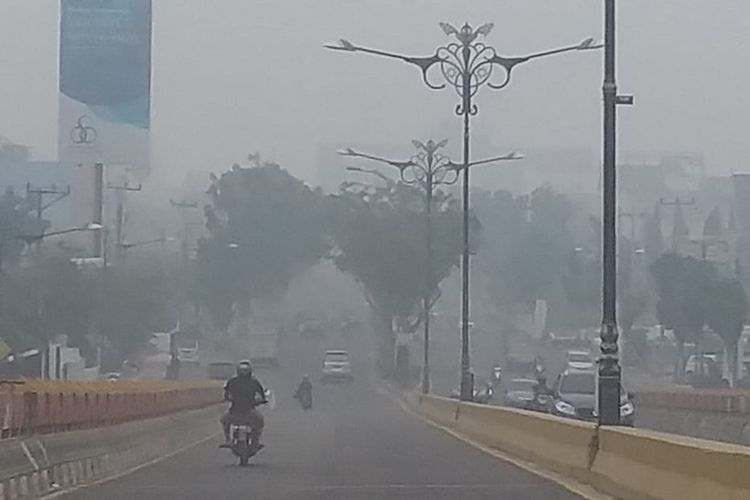 Kabut asap pekat dengan jarak pandang sekitar 300 meter di Jalan Jenderal Sudirman, Kota Pekanbaru, Riau, Jumat (13/9/2019).