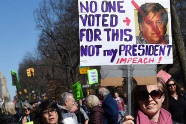 Seorang pendemo membawa poster penolakan terhadap Presiden AS Donald Trump dalam aksi unjuk rasa di New York, Senin (20/2/2017). 