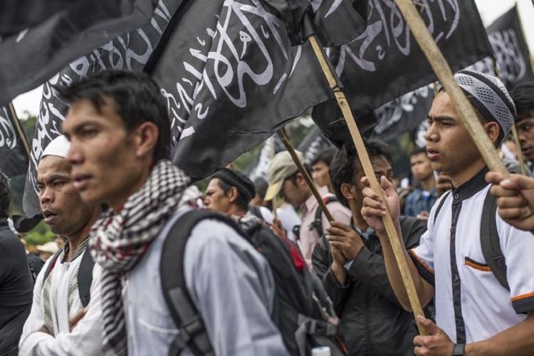 Massa dari Hizbut Tahrir Indonesia membawa bendera saat demo di Jakarta pada 18 Juli 2017. Mereka menentang rencana pemerintah yang akan membubarkan HTI. 