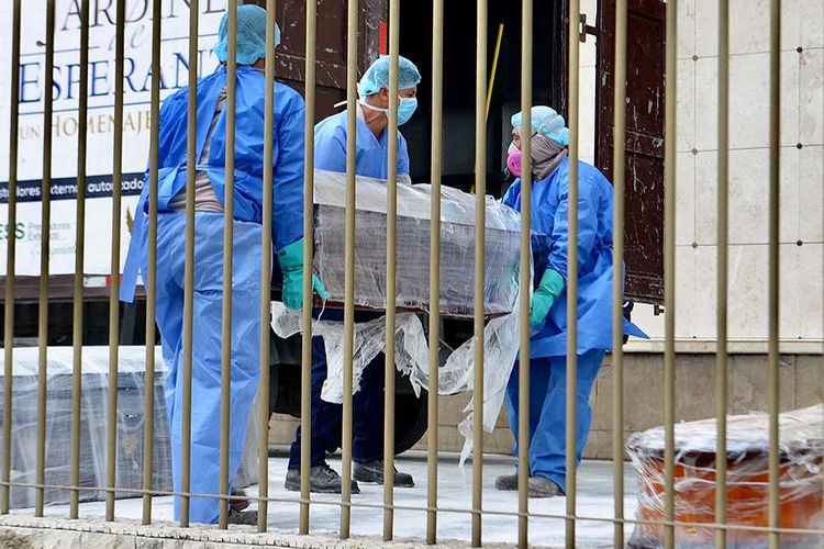 Sejumlah petugas dengan mengenakan alat pelindung diri (APD) membawa peti mati dari seseorang yang diduga meninggal akibat virus corona, di sebuah pemakaman di Guayaquil, Ekuador, Rabu (1/4/2020). Otoritas Ekuador dalam beberapa hari terakhir telah mengumpulkan setidaknya 150 jenazah dari jalan-jalan dan rumah para warga di Kota Guayaquil, di tengah lonjakan kasus virus corona di wilayah tersebut.