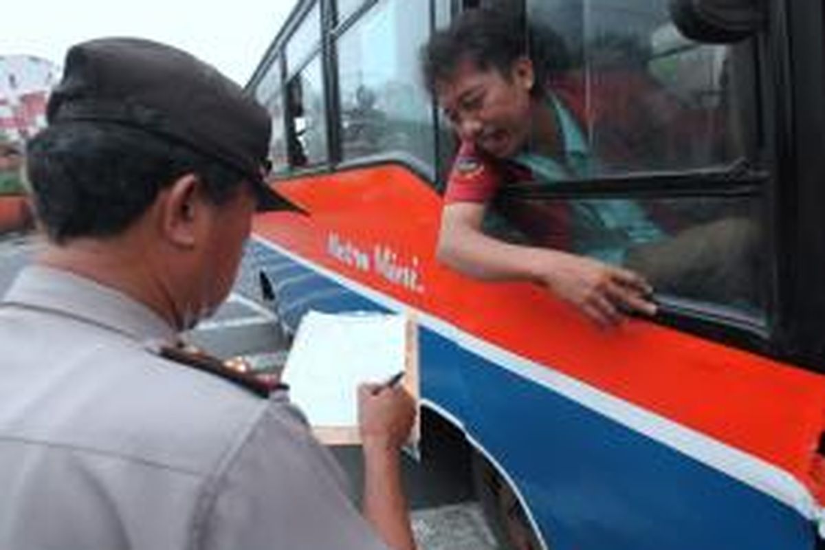 Polisi dari polsek Kebayoran Baru mendata identitas pengemudi Metromini yang menunggu penumpang di Terminal Blok M, Jakarta Selatan, Kamis (13/12/12). Kegiatan yang juga diisi dengan menempelkan stiker informasi nomor telepon kantor polisi itu ditujukan untuk mencegah dan menekan kejahatan yang biasa terjadi di angkutan umum.