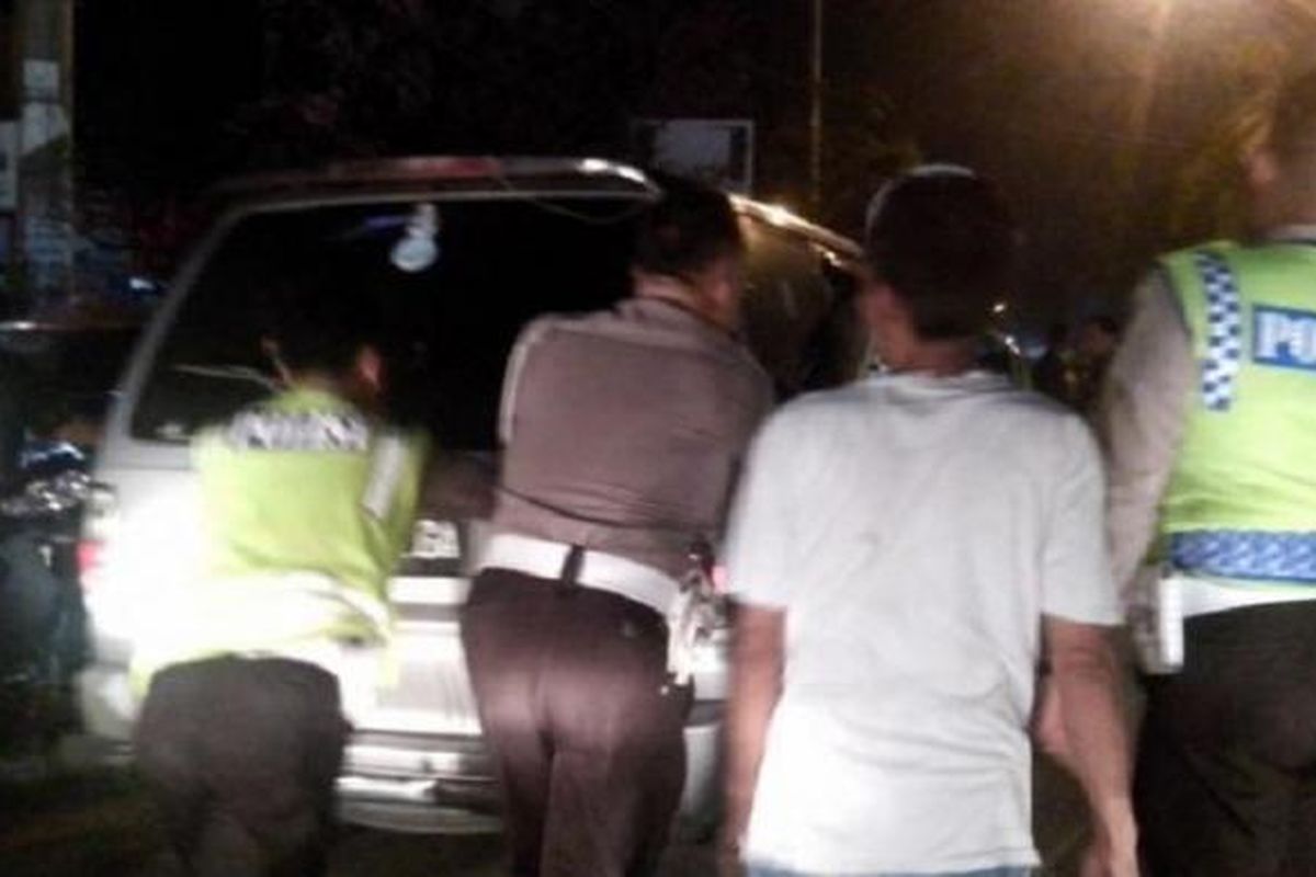 Petugas kepolisian mendorong mobil yang diduga penyebab kemacetan di Jalan Jamin Ginting, Selasa (30/6/2015) malam 