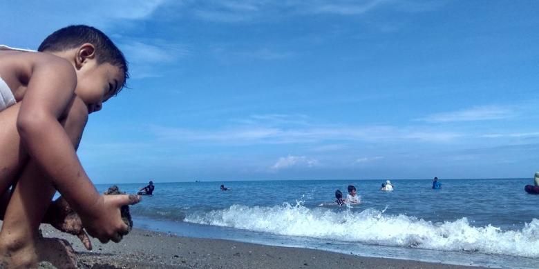 Seorang anak bermain pasir di Pantai Ujong Blang, Kecamatan Banda Sakti, Lhokseumawe, Aceh, Minggu (25/12/2016)