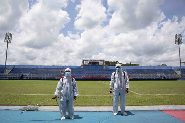 Dua petugas penyemprotkan disinfektan ke bench pemain sebelum laga Piala Mentora 2021 dimulai di Stadion Kanjuruhan Kabupaten Malang, Jawa Timur, Sabtu (27/03/2021) siang. 