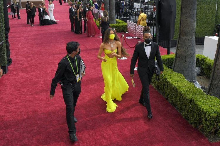 Aktris Zendaya ketika melenggang di karpet merah Oscar, Minggu (25/4/2021) sore waktu Los Angeles. Ia terlihat mengenakan masker berwarna senada dengan gaunnya ketika tidak berada di depan kamera.