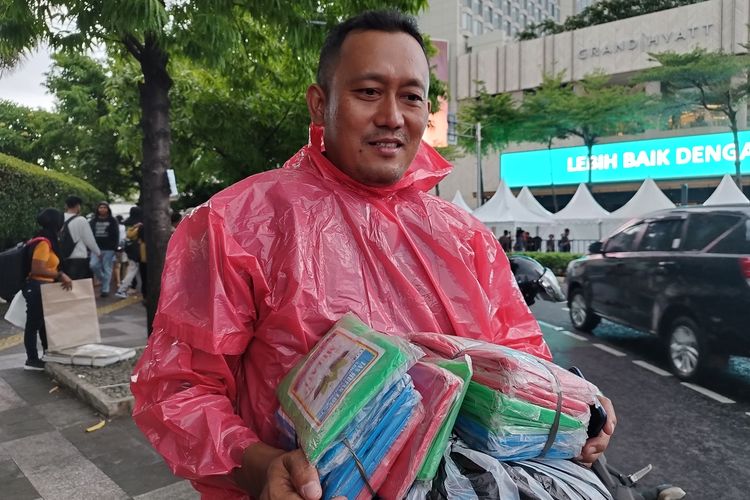 Pedagang jas hujan Basir (40) saat diwawancarai di kawasan Bundaran HI, Menteng, Jakarta Pusat, Minggu (31/12/2023).