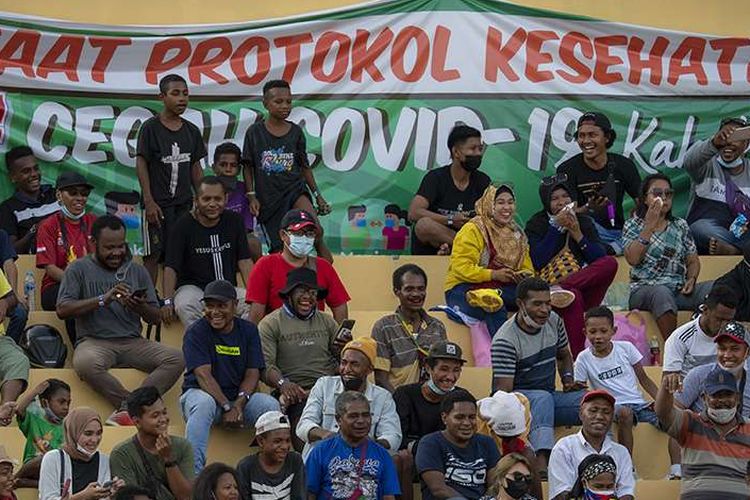 Warga menyaksikan pertandingan babak enam besar sepak bola putra PON XX Papua 2021 antara Tim Papua melawan Tim Aceh di Stadion Mandala, Kota Jayapura, Papua, Rabu (6/10/2021). Sejumlah laporan dari PON XX Papua menunjukkan sebagian penonton yang hadir di venue pertandingan ditemukan masih lalai terhadap protokol kesehatan, seperti tidak mengenakan masker dan mengabaikan pembatasan jarak.