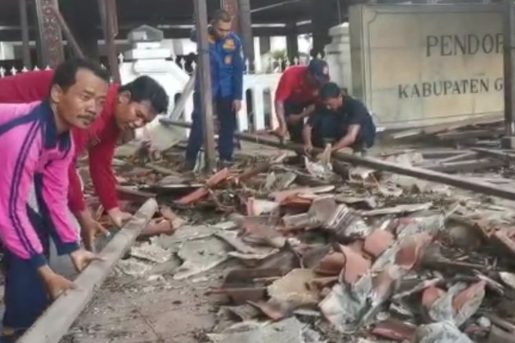 Petugas gabungan pada saat membersihkan material sebagian atap pendopo Kabupaten Gresik, Jawa Timur, yang ambruk, Minggu (13/11/2022).