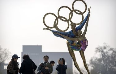 Para pengunjung berfoto di patung atlet dengan logo Olimpiade di dekat markas Komite Olimpiade Beijing (BOCOG), Kamis (18/11/2021).