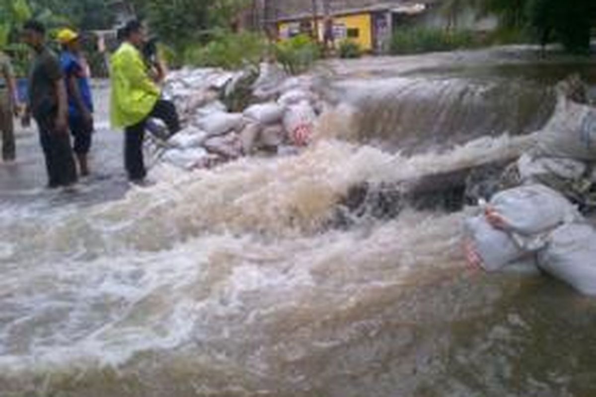 Tanggul tambahan berisi pasir di Kali Cipinang, Makassar, Jakarta Timur, Selasa (28/1/2014) tak sanggup menahan debit air sehingga air melimpas ke jalan.