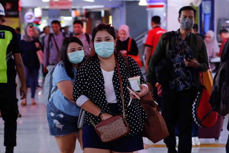 Calon penumpang kereta api mengenakan masker di Stasiun Gambir, Jakarta, Jumat (31/1/2020). PT KAI Daop 1 Jakarta membagikan masker gratis pada calon penumpang dalam rangka mengantisipasi penyebaran virus corona.