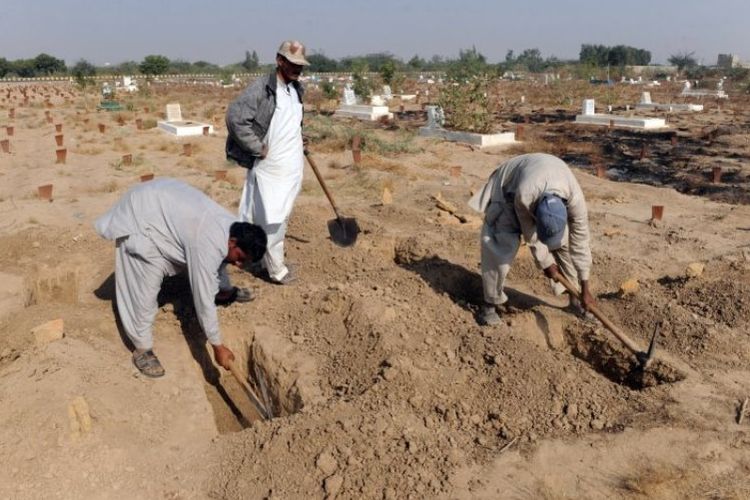 Para relawan menggali liang lahat untuk jenazah bayi yang ditemukan di Pakistan pada 2002.