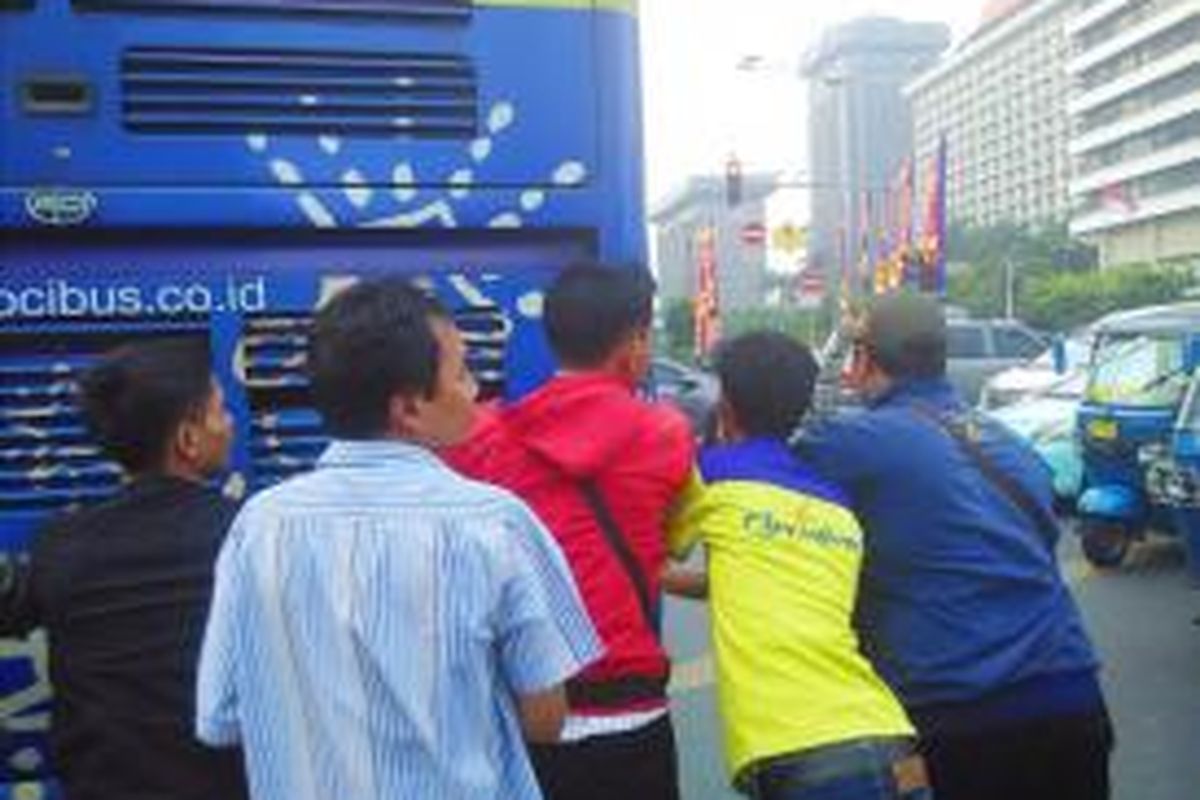 Sejumlah penumpang bersama petugas bus City Tour Jakarta mendorong bus yang mogok di perempatan Sarinah, Rabu (1/7/2015) sore