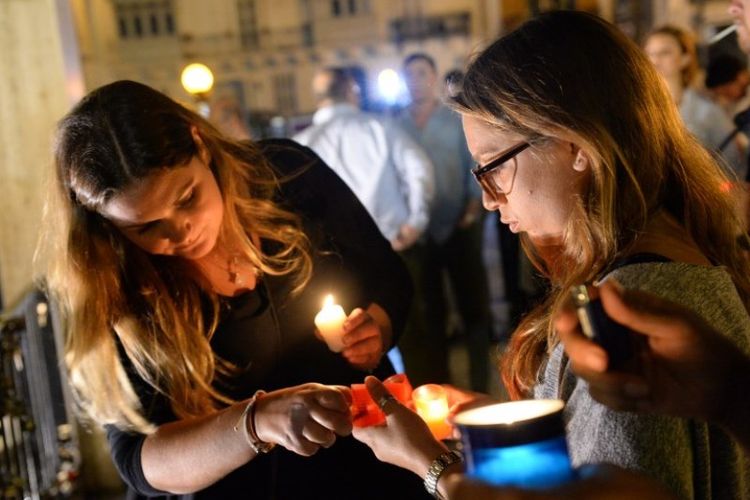 Seorang perempuan menyalakan lilin dalam doa bersama di kota Sliema, Malta untuk mengenang jurnalis Daphne Caruana Galizia yang tewas akibat bom mobil.