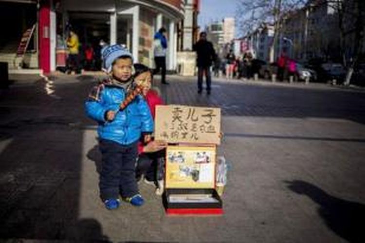 Meng Xiangyan (29) berdiri bersama anak laki-lakinya di salah satu sudut jalan di kota Qingdao, China. Perempuan itu berusaha menjual anaknya demi mencari biaya pengobatan leukemia yang diderita anak perempuannya.