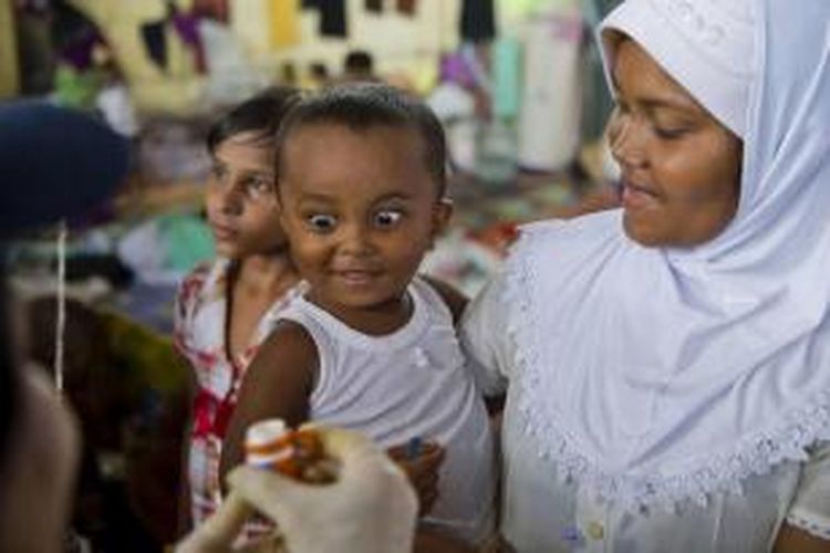 Seorang anak etnis Rohingya (kiri) yang digendong ibunya diberi vitamin A dari tim medis International Organization for Migration, di Kuala Langsa, Aceh, Senin (18/5/2015). Anak-anak ini merupakan bagian dari para pengungsi Rohingya yang meninggalkan kampung halaman mereka di Rakhine, Myanmar, karena konflik.